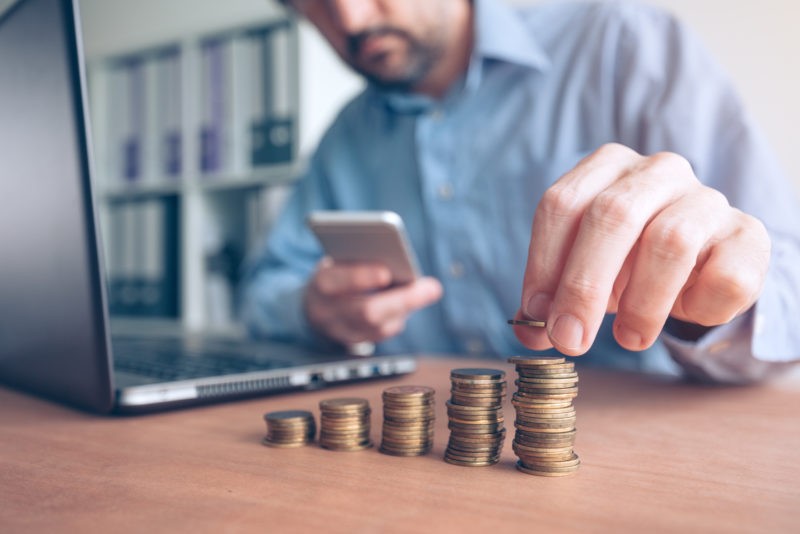 Financial Advertising person stacking change while looking at smartphone
