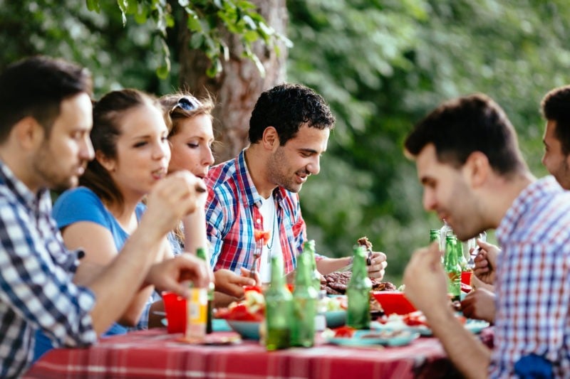 group-of-people-eating-food-together-outside-at-a-picnic-table