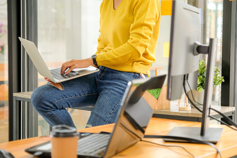 woman seating on the desk and typing