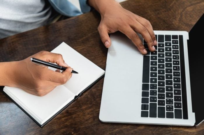 african american man holding pen and using laptop
