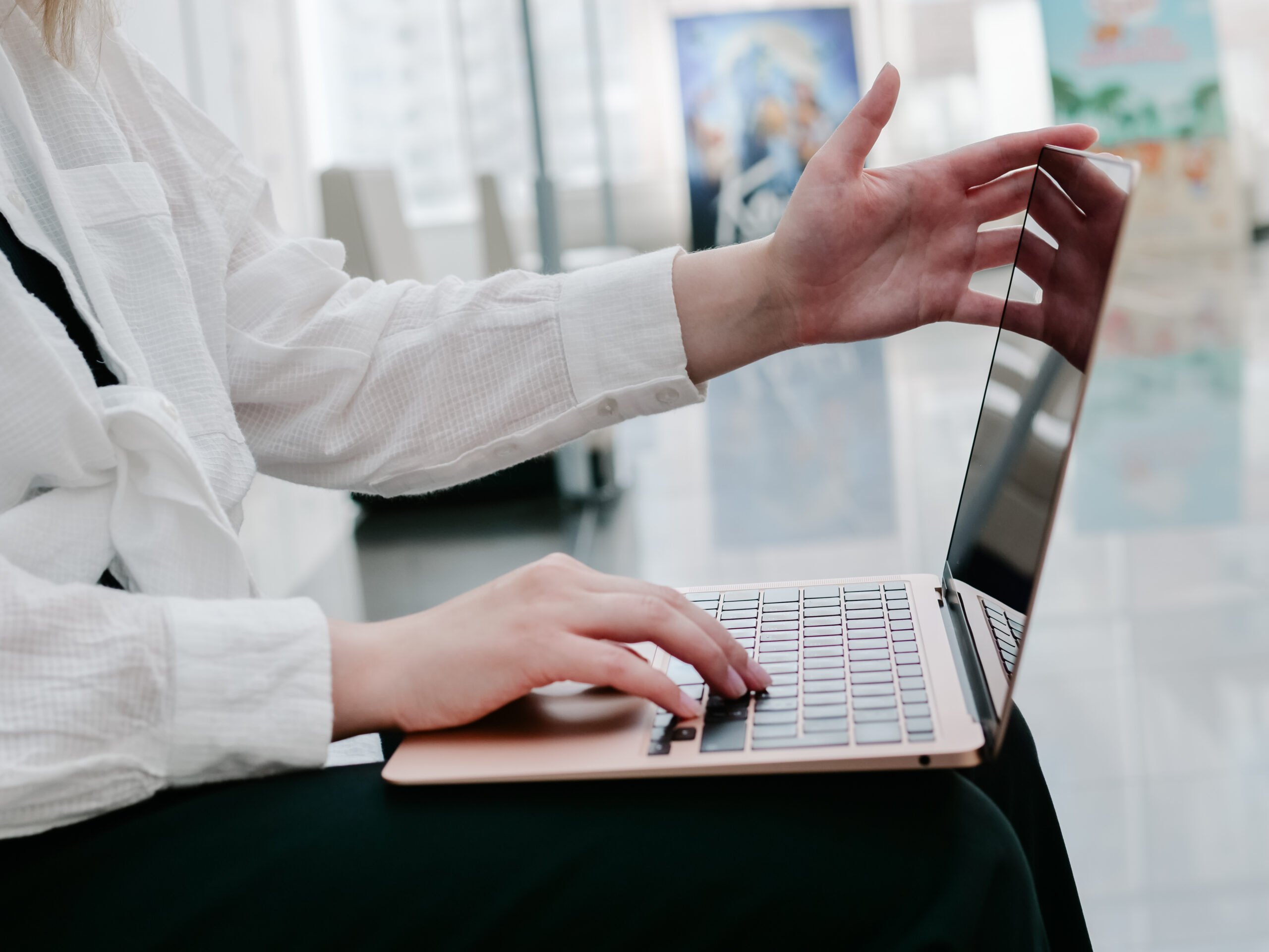 Woman holding a laptop in her hands and typing on the keyboard