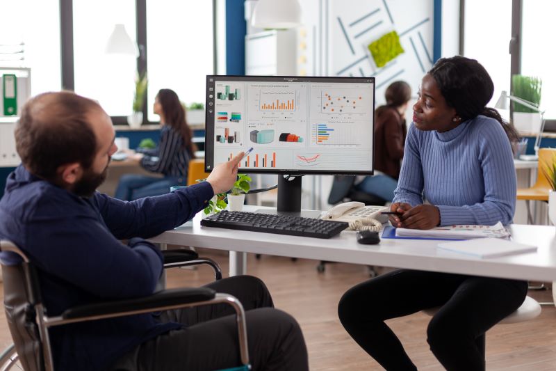 coworkers talking about analytics at laptop