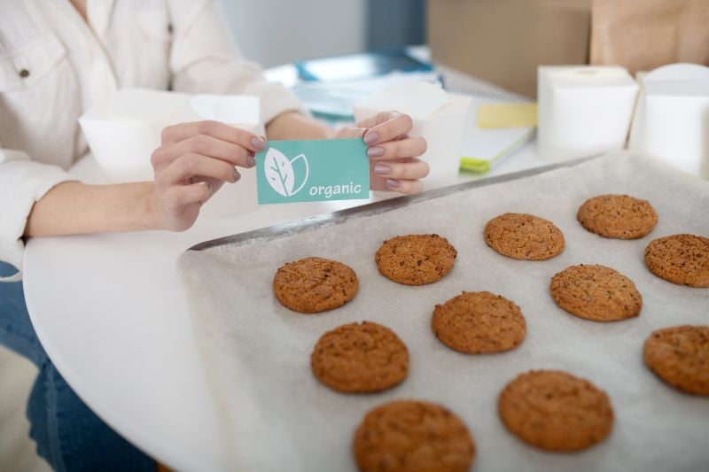 female hands holding a card near tray with homemade cookies