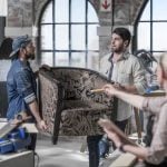 manager directing male workers carrying armchair