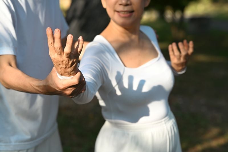 smiling senior woman practicing posture during tai chi