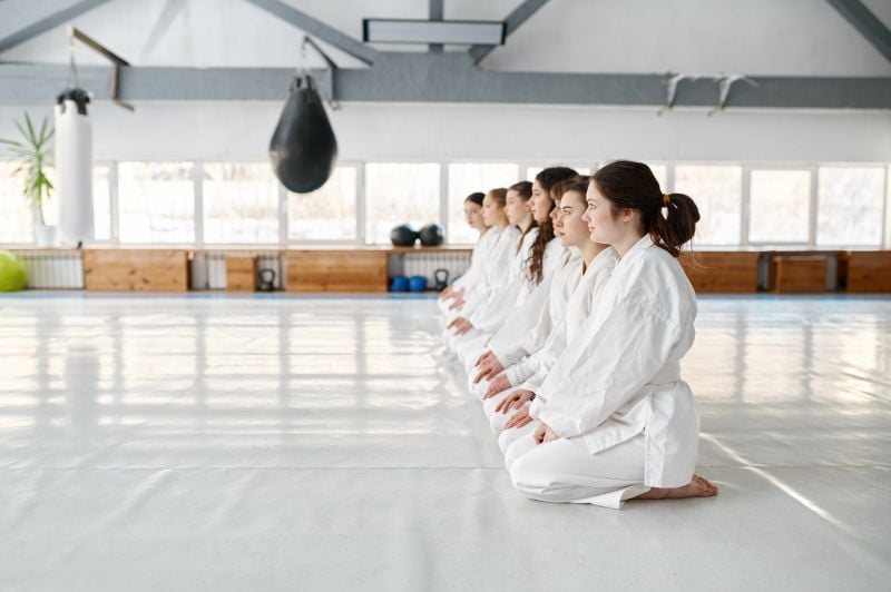 young aikido students wearing kimono sitting on floor