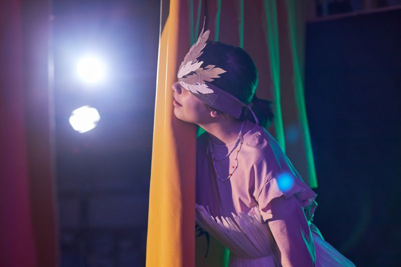girl in costume hiding behind curtains